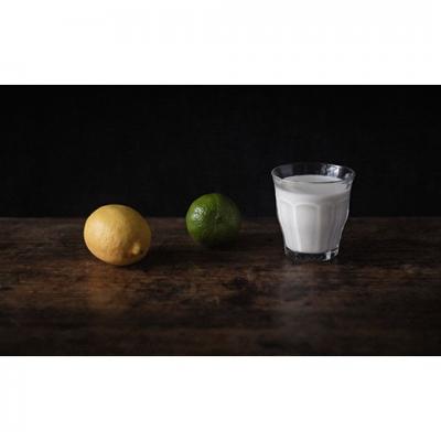 Un citron jaune, un citron vert et un verre de lait